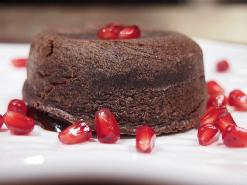 Molten Chocolate Cake on plate topped with pomegranate seeds.