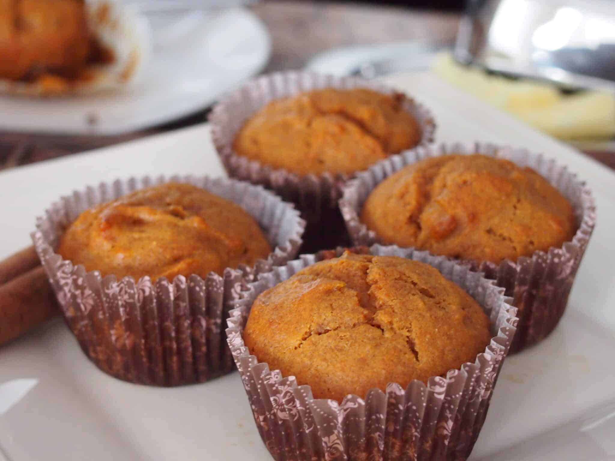 Four Carrot muffins on white dish.