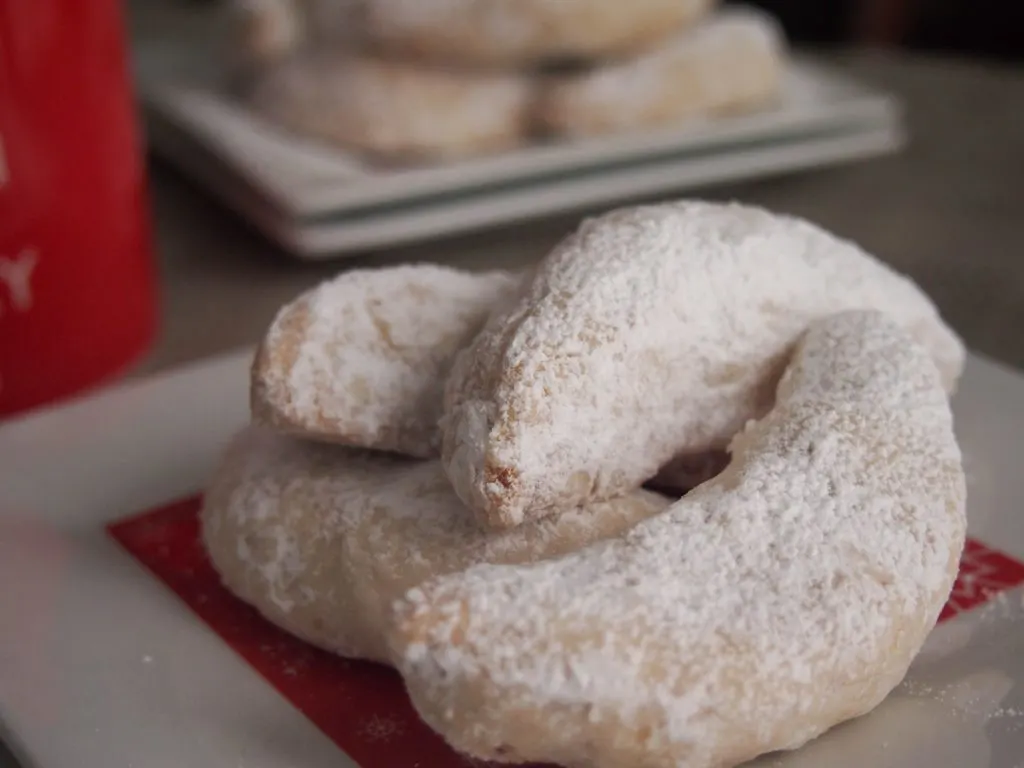 Crescent shaped Christmas cookies rolled in confectioners' sugar.