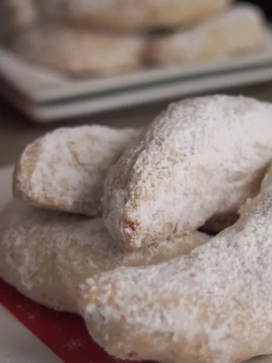 Crescent shaped Christmas cookies rolled in confectioners' sugar.