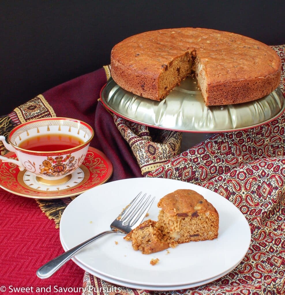 Partially eaten slice of date cake served with a cup of tea. 