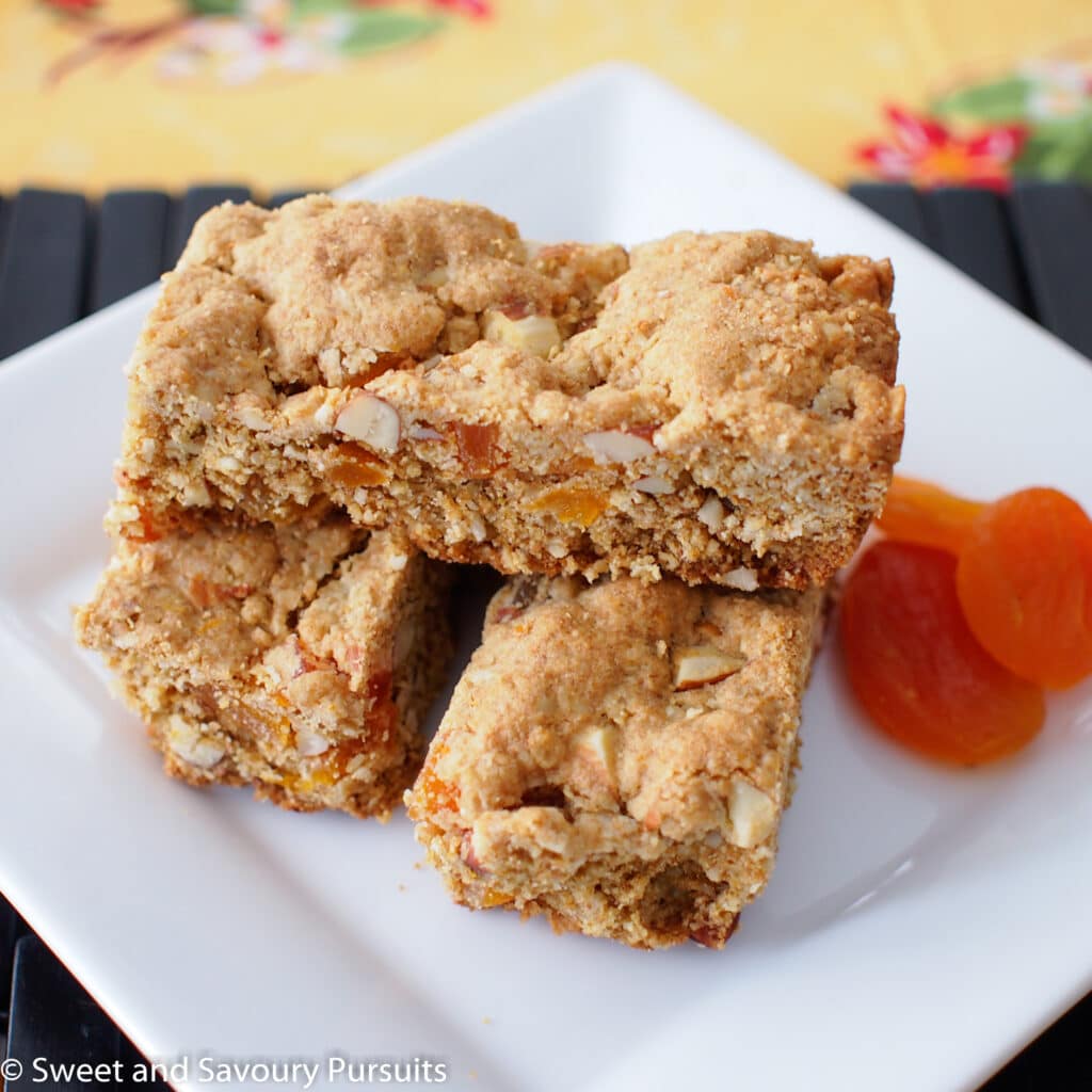 Whole Wheat Apricot and Almond Bars on white dish served with dried apricots on the side.