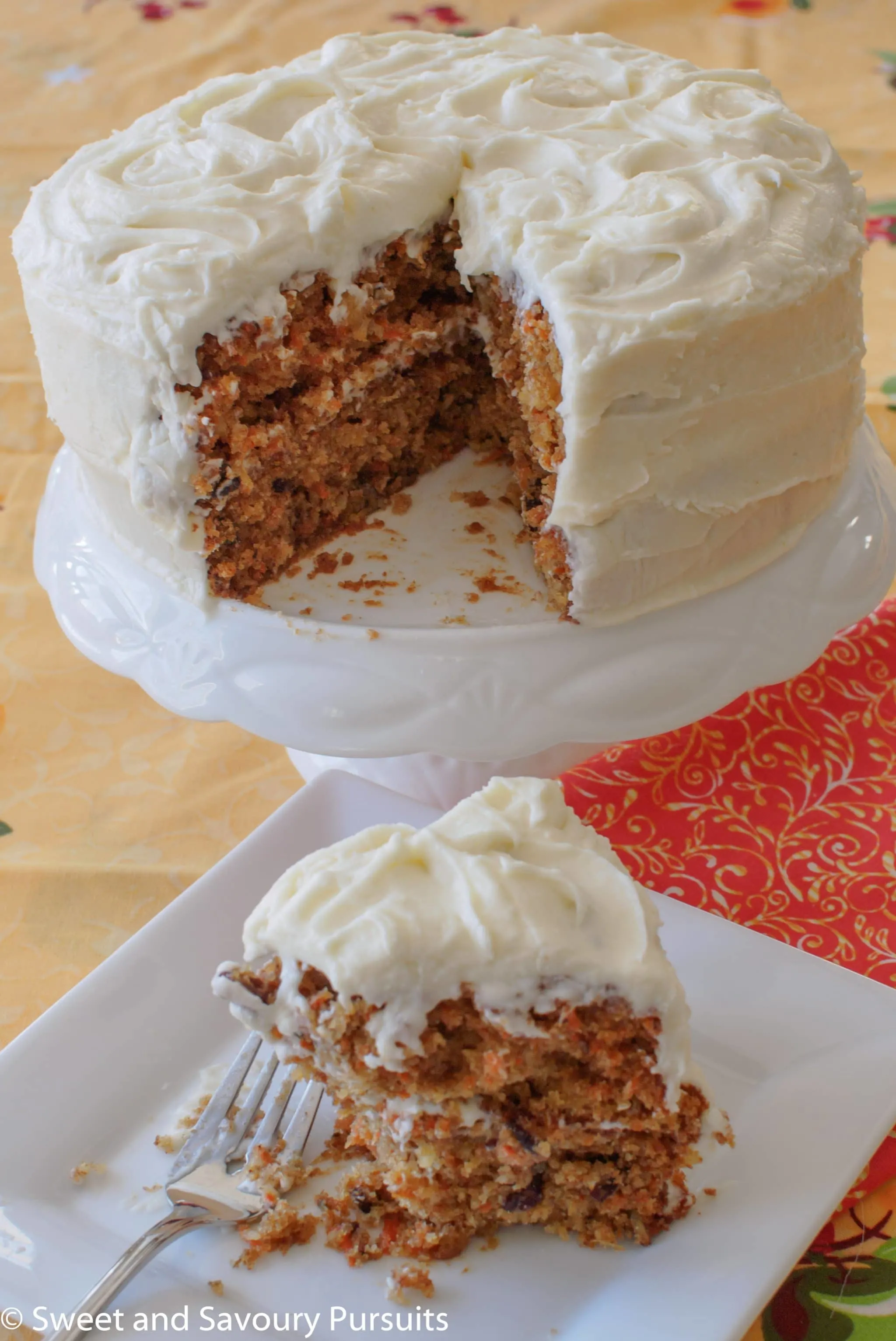 Carrot Cake with Cream Cheese Frosting on platter with slice removed.