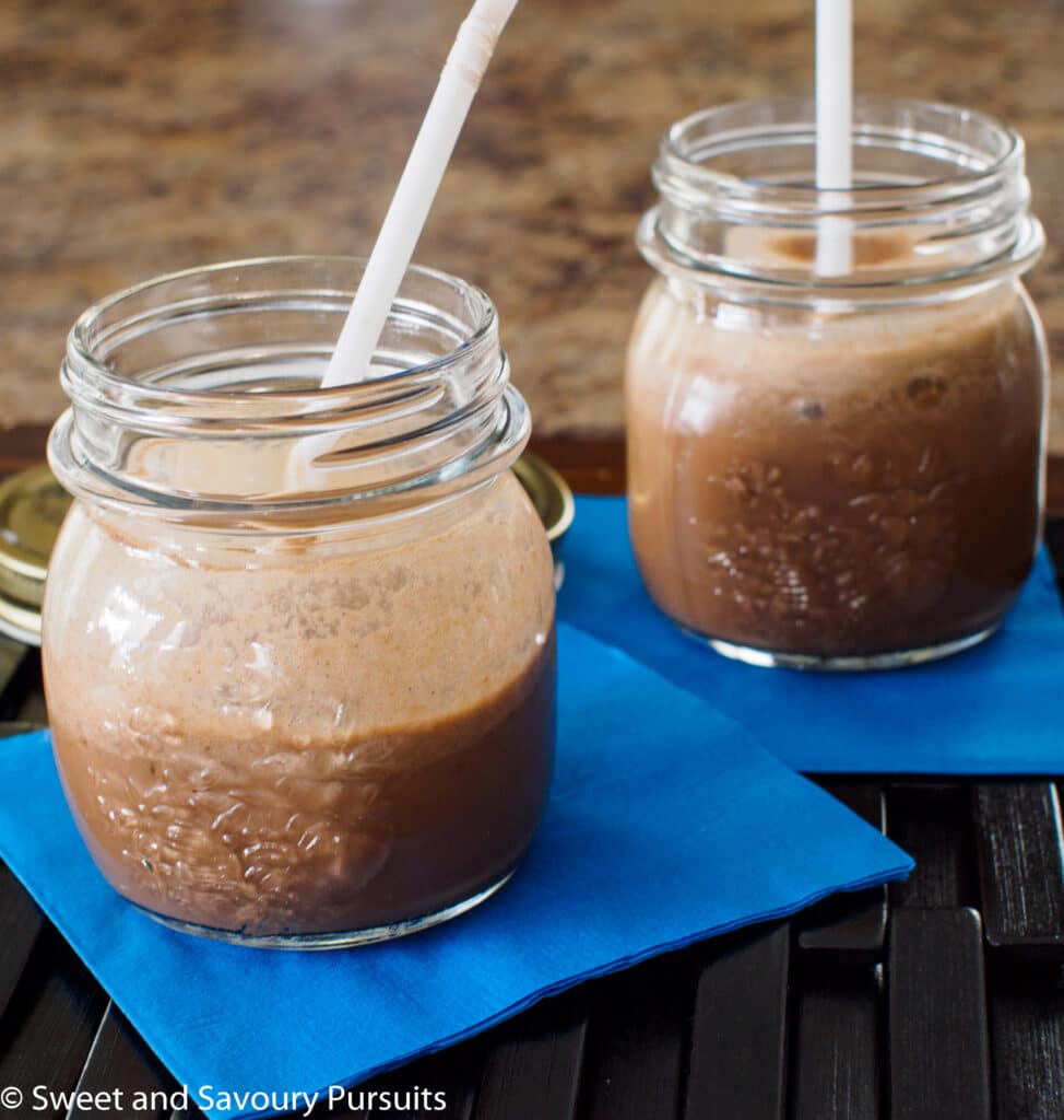 Two servings of a coffee flavored smoothie served in small mason jars.