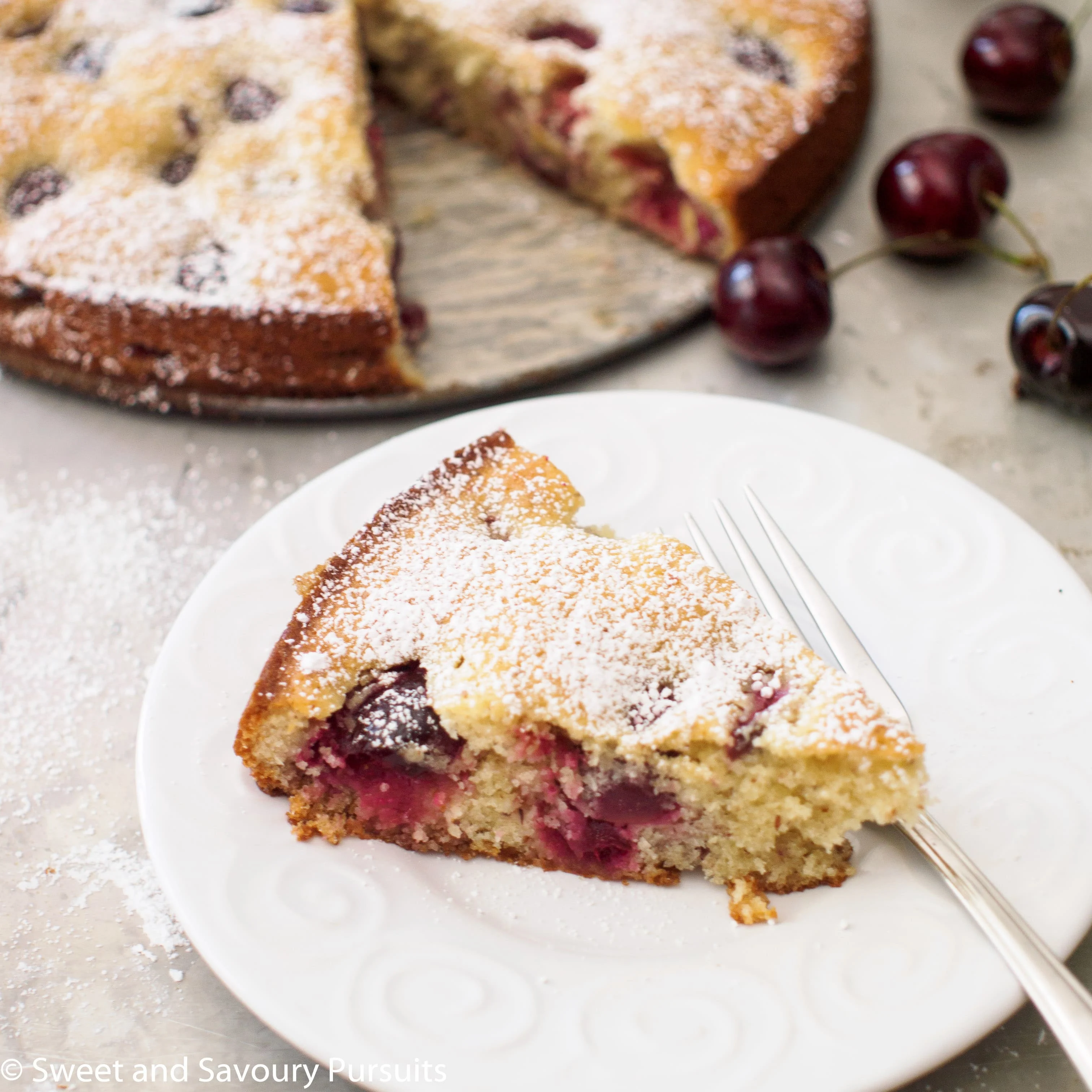 Slice of Cherry Almond Cake on white plate.