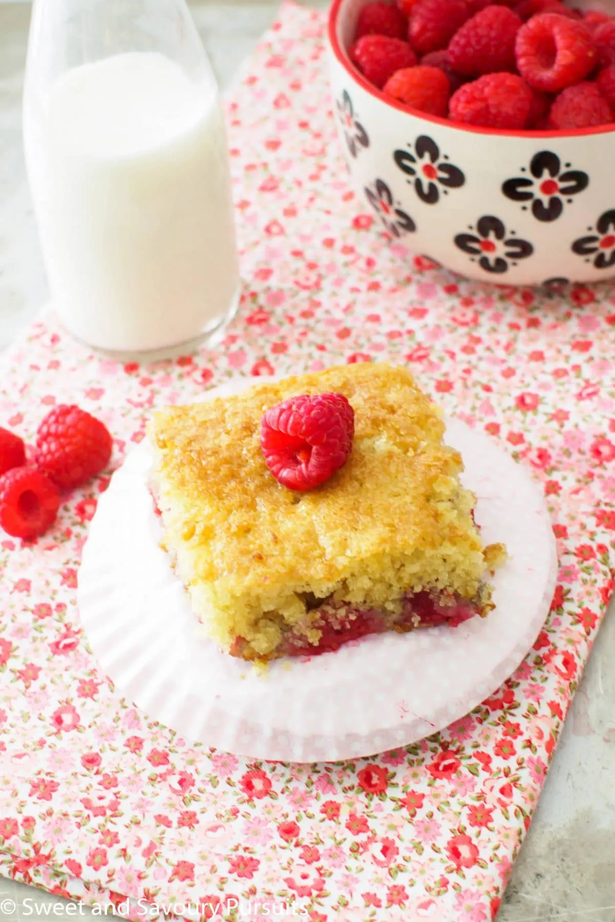 Raspberry Buttermilk Cake served with bowl of fresh raspberries.