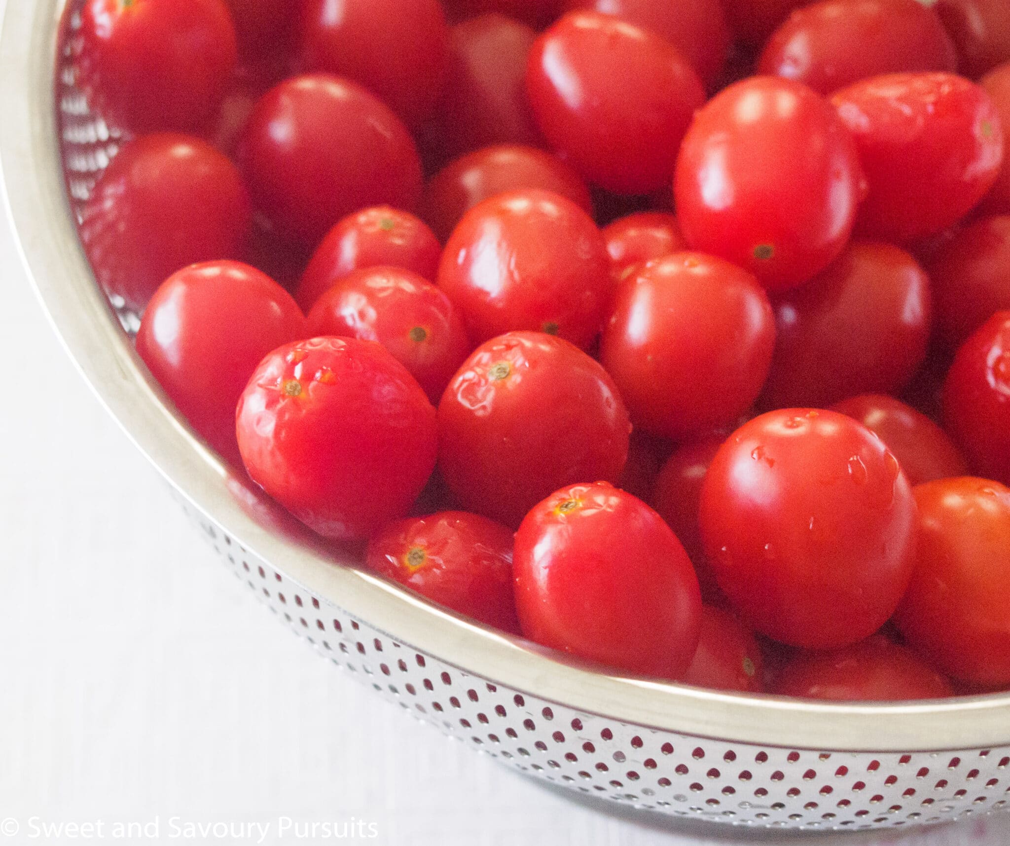 Freshly rinsed grape tomatoes in a colander.