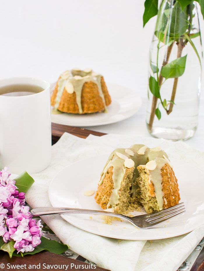 Two small almond and green tea cakes on small dishes.