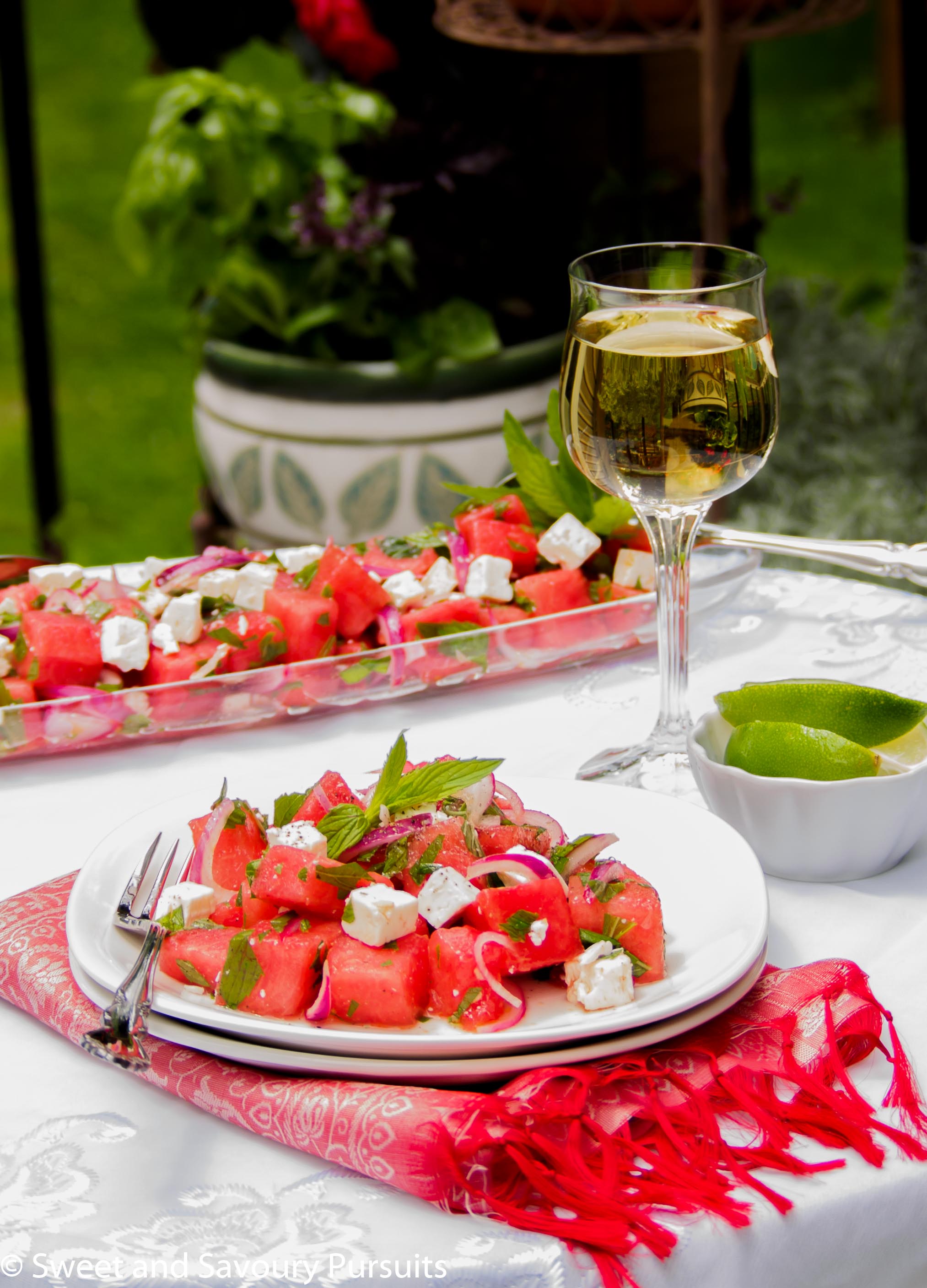 Plate of salad made with watermelon and feta cheese served outdoors.