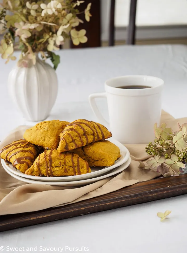 Plate of pumpkin scones on tray served with a cup of coffee.