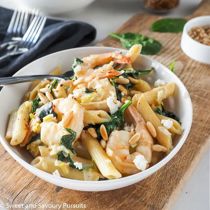 Pasta bowl topped with shrimp, spinach and goat cheese. 