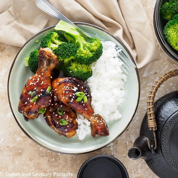 Dish of Sticky Hoisin-Soy Chicken Drumsticks with broccoli and rice.