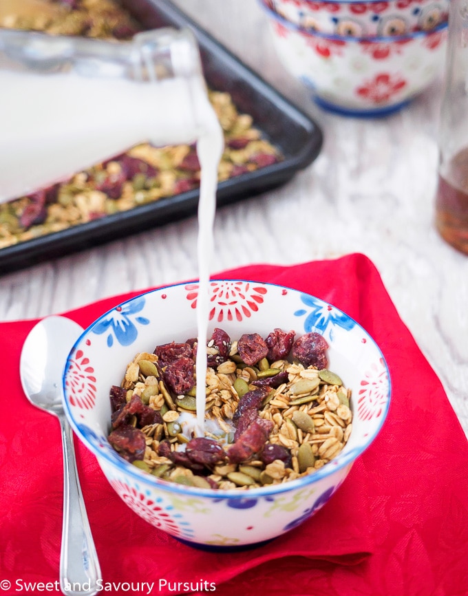 Bowl of Healthy Pumpkin Seed Granola being topped with milk.