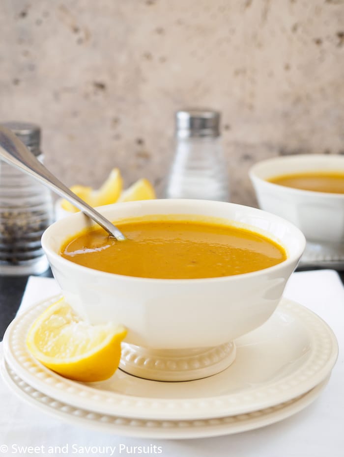 A bowl of Sweet Potato and Red Lentil Soup served with a wedge of lemon.