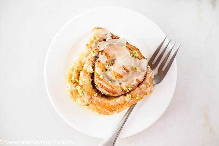 Freshly baked Tahini and pistachio cinnamon roll on small white dish.