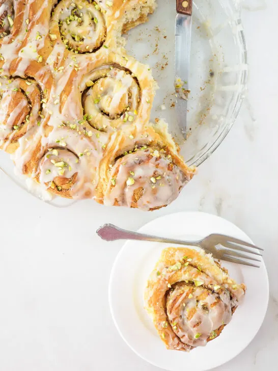 Freshly baked rolls in baking dish and one on small dish.