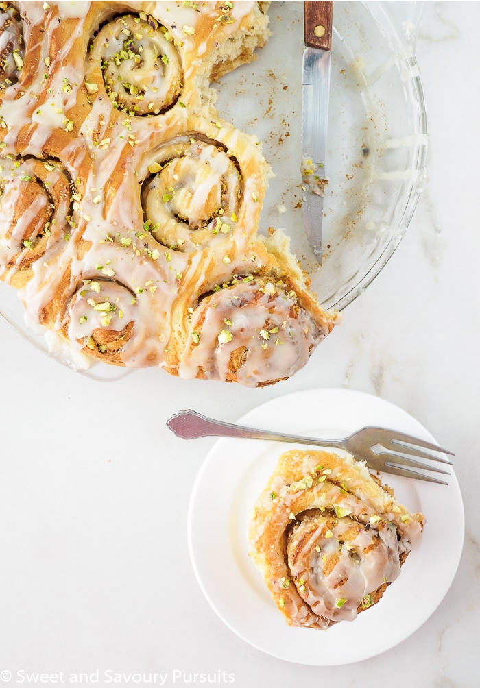 Freshly baked rolls in baking dish and one on small dish.