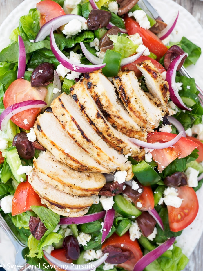 Greek salad topped with grilled chicken breast. 