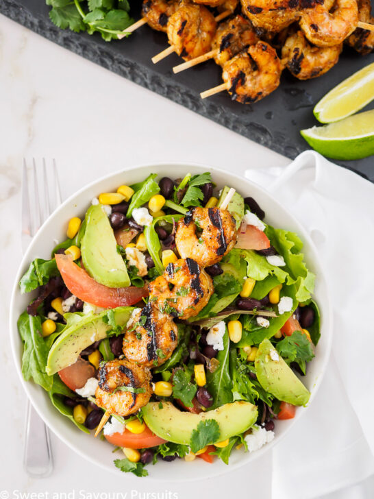 Southwestern Grilled Shrimp Salad served in bowl with extra shrimp and lime on the side.