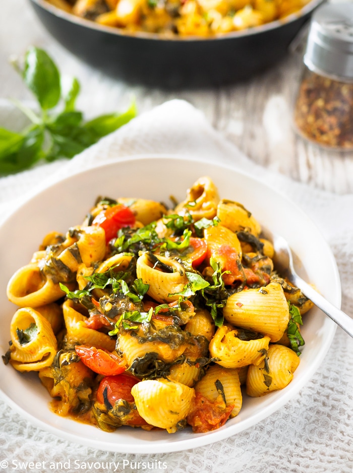 Creamy Tomato and Spinach Pasta served in white bowl.