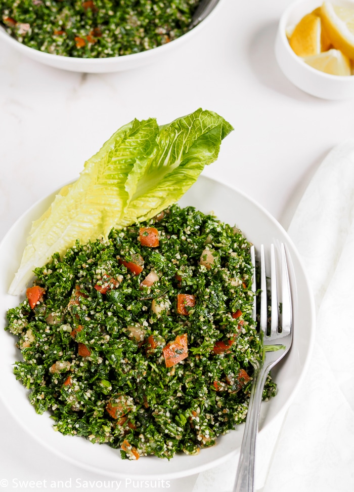 Tabbouleh served in bowl with Romaine lettuce leaves to the side.