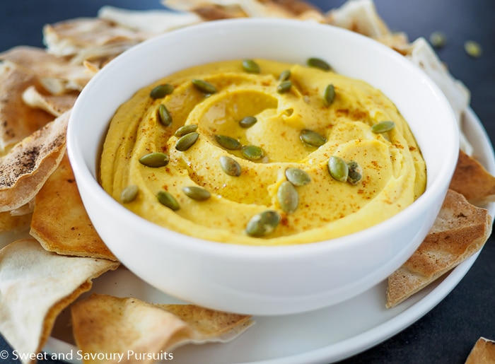 Butternut squash dip in white bowl served with pita chips.