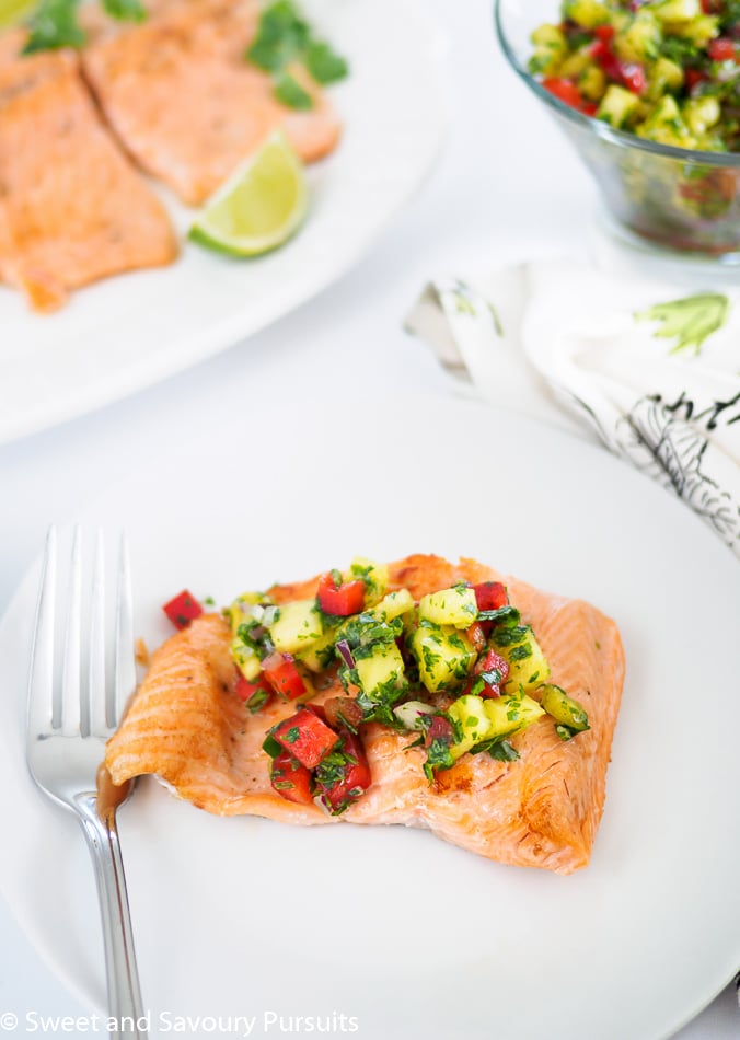 Piece of trout fillet on plate topped with pineapple salsa.