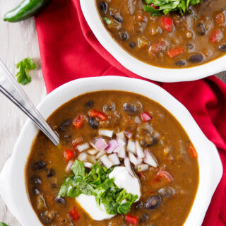 Bowls of Black Bean Soup topped with chopped cilantro, onion and sour cream.