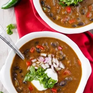 Bowls of Black Bean Soup topped with chopped cilantro, onion and sour cream.