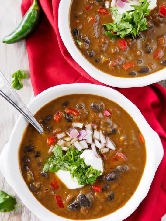 Bowls of Black Bean Soup topped with chopped cilantro, onion and sour cream.
