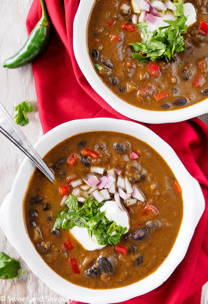 Bowls of Black Bean Soup topped with chopped cilantro, onion and sour cream.