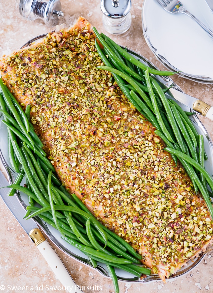 Filet of Pistachio Crusted Salmon on dish with green beans on the sides.