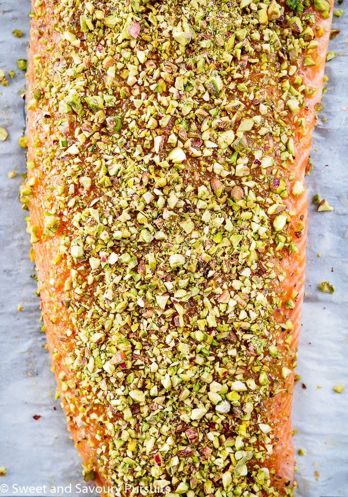 Filet of uncooked salmon with pistachio crust on baking tray.