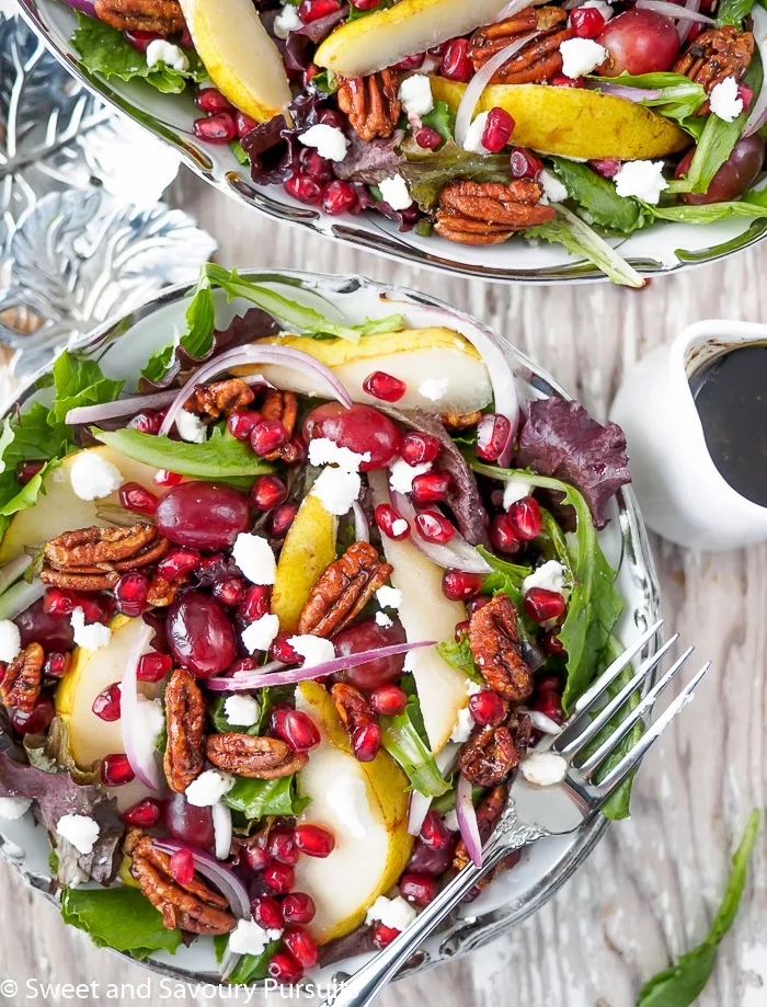 Top view of a salad with pomegranate seeds, pears, grapes and pecan.