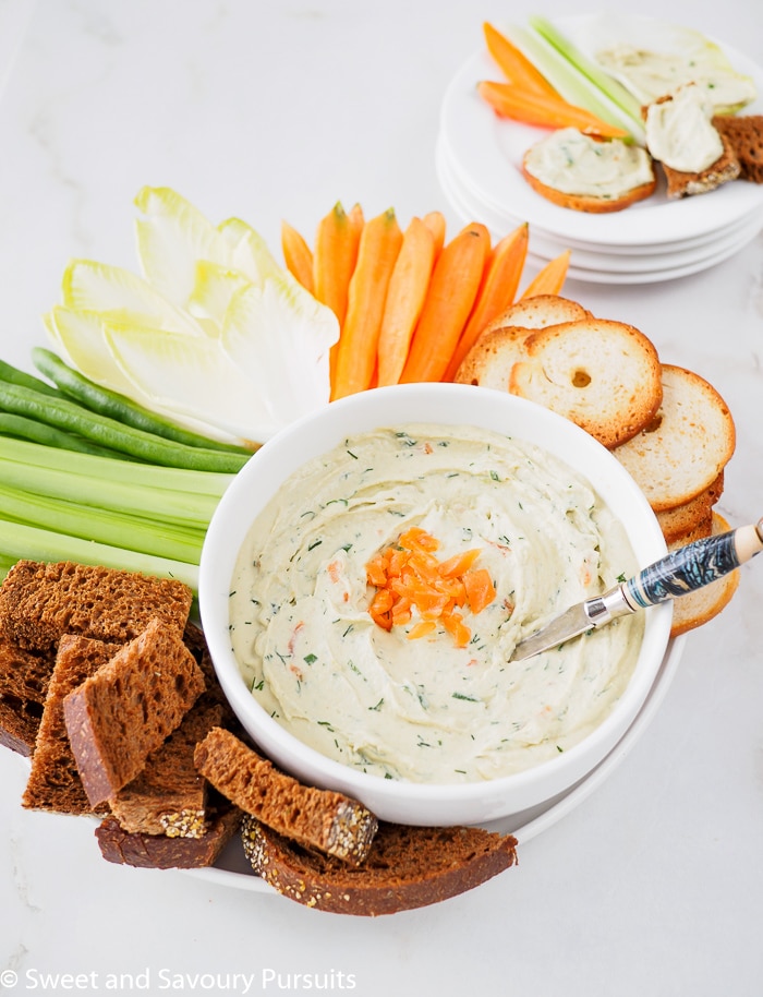 Close-up of a Smoked Salmon Dip served with fresh vegetables, bagel crisps and pumpernickel bread.