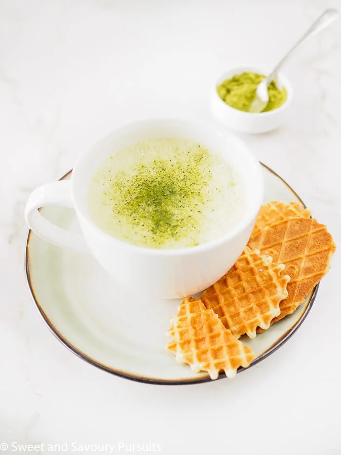 A large cup of Matcha green tea latte served with cookies.