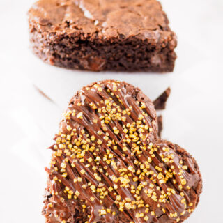 Close-up of heart shaped Chocolate Spiced Brownies with chocolate drizzle and gold sprinkles.