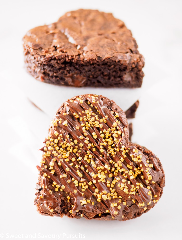 Close-up of heart shaped Chocolate Spiced Brownies with chocolate drizzle and gold sprinkles.