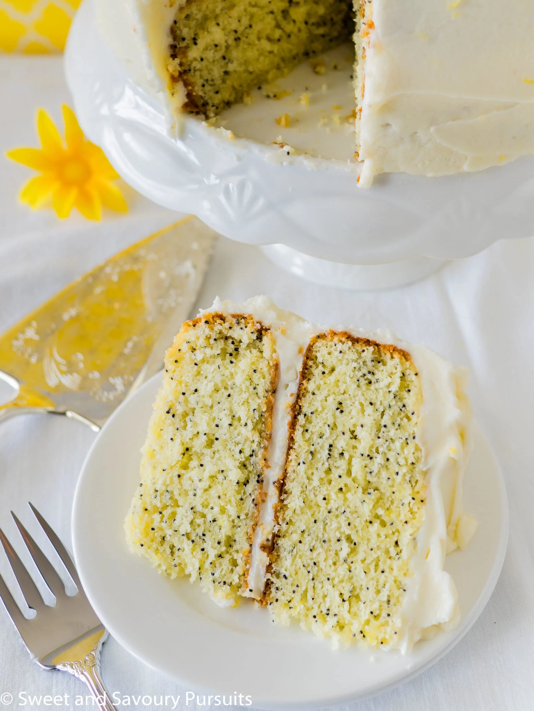 Slice of a layered lemon poppy seed cake with cream cheese frosting.