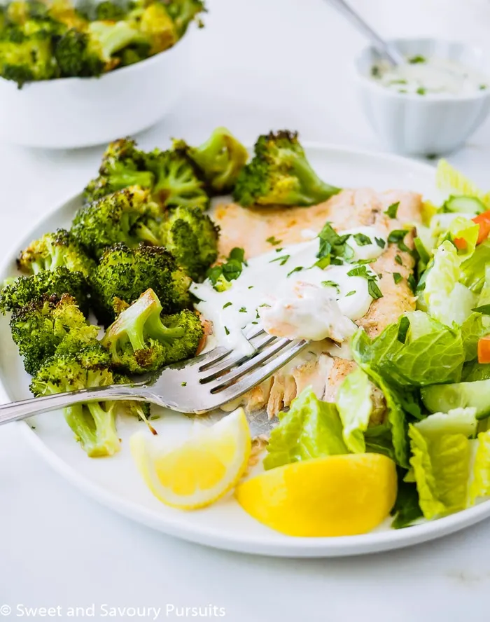 Baked Rainbow Trout Fillets with Roasted Broccoli and salad on dish.