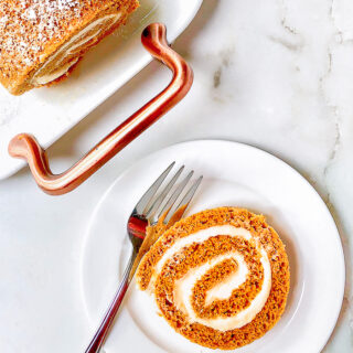 A slice of a rolled pumkin cake stuffed with a maple cream cheese swirl.