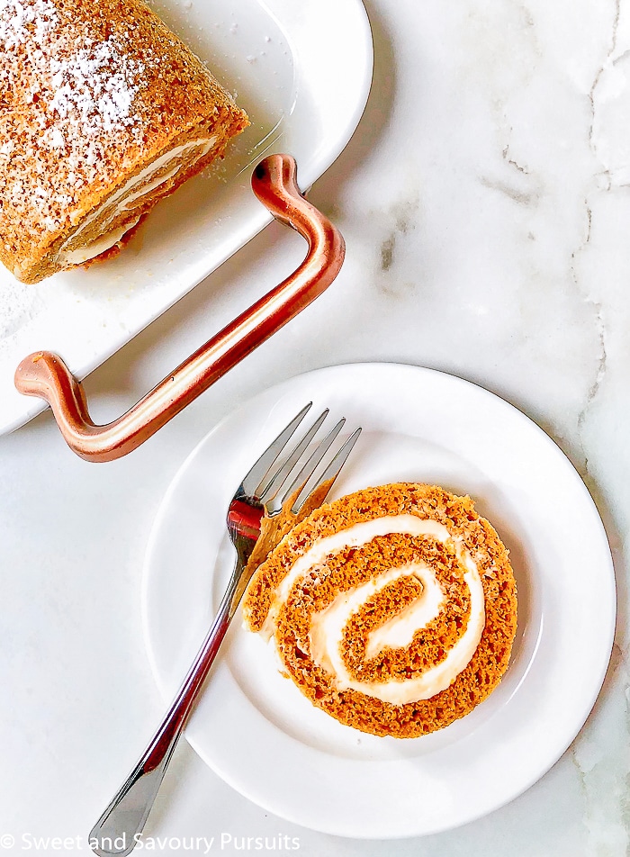 A slice of a rolled pumkin cake stuffed with a maple cream cheese swirl.