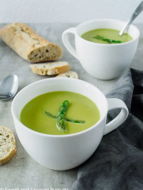 Creamy asparagus soup in white mugs.