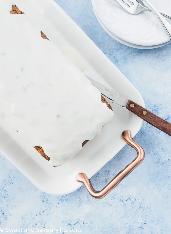 Top view of an iced carrot cake loaf served on a white platter.