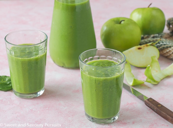 Pineapple Spinach Smoothie poured into two small glasses with larger bottle in background.