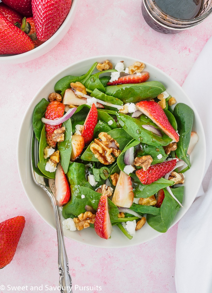 Strawberry Spinach Salad topped with walnuts and dressed with a balsamic dressing.