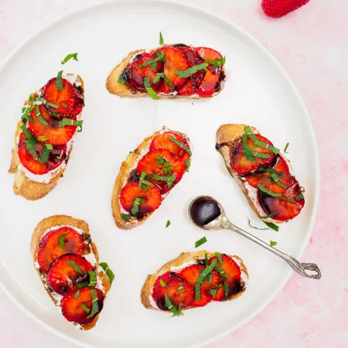 Strawberry Goat Cheese Crostini drizzled with a balsamic reduction on a plate.