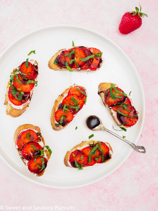 Strawberry Goat Cheese Crostini drizzled with a balsamic reduction on a plate.