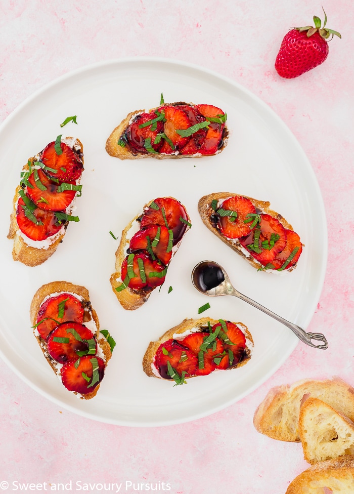 Plater of crostini topped with goat cheese and sliced strawberries.