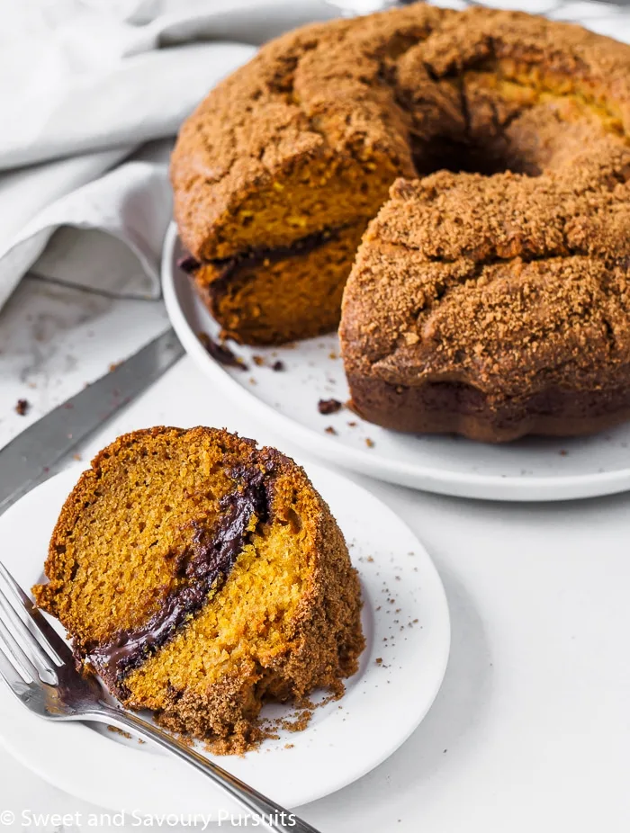 A pumpkin bundt cake with a melted chocolate swirl in the middle and topped with a crumbly brown sugar and spice mixture.